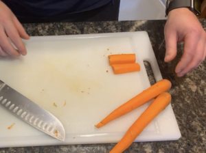 Peeled whole carrots and a halved carrot section on a cutting board