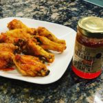 Glazed habanero jam wings on a white plate with the jam jar