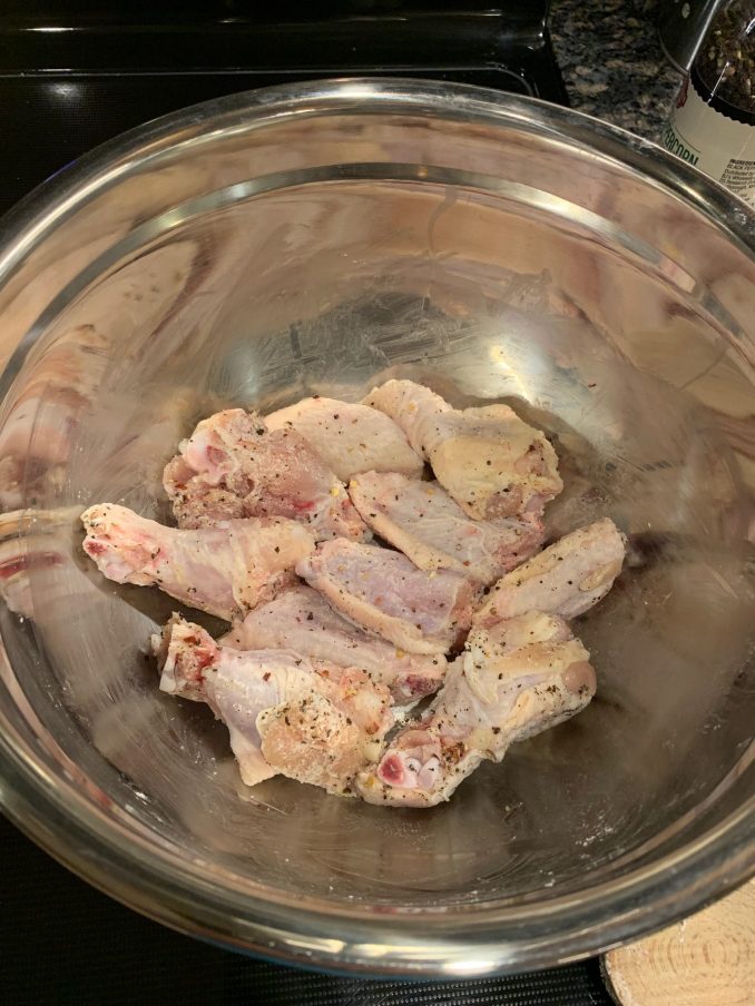 Raw chicken wings tossed with baking powder, salt and pepper in a bowl