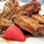 Strawberry balsamic chicken wings with sesame seeds and a fresh strawberry