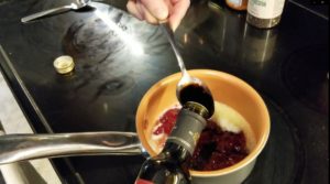 Adding a spoonful of balsamic vinegar to strawberry jam in the pot